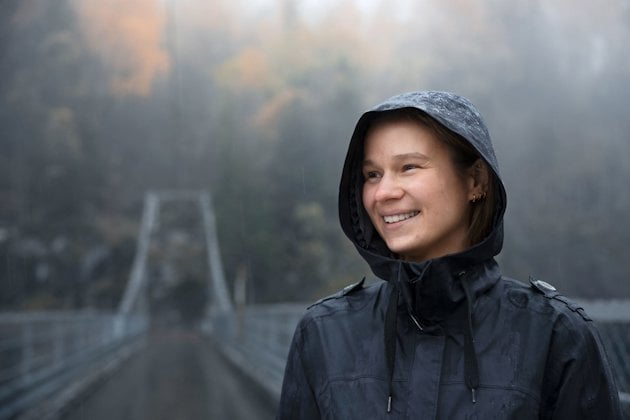 a person smiling with a bridge in the background