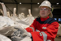 a man wearing a hard hat and protective gear holding a pile of plastic bags